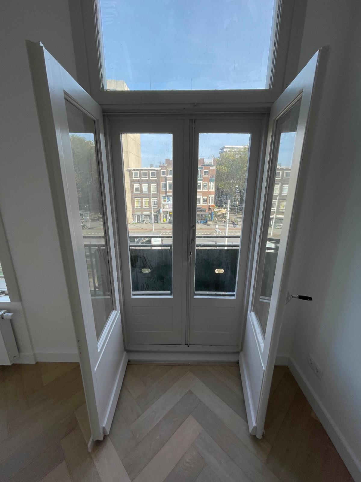 Balcony doors with new white window frames and a view over Rotterdam after an energy upgrade