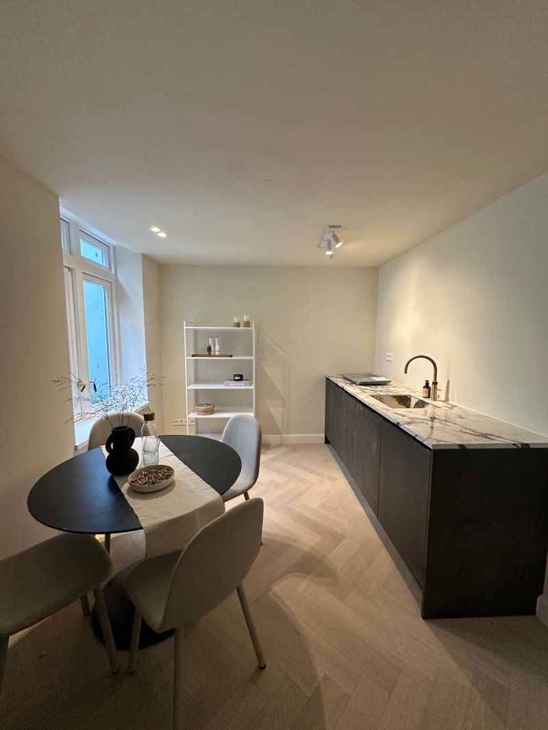 Woonkeuken met eettafel, marmeren werkblad en visgraatvloer in een gerenoveerd Amsterdams appartement