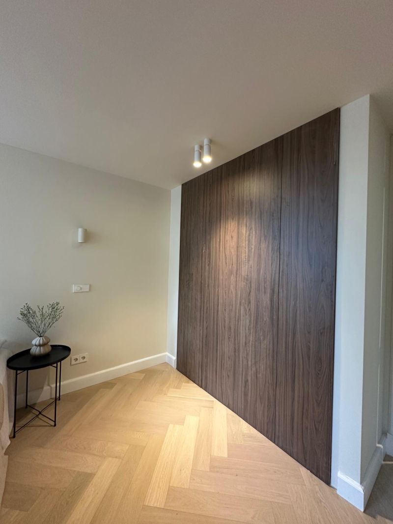 Inbouwkast van vloer tot plafond met donkere houten fronten in een slaapkamer
