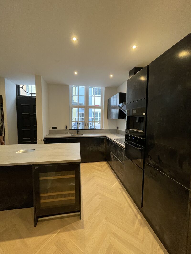 Woonkeuken met kookeiland en zwarte kasten na een complete renovatie van een woning in Den Haag