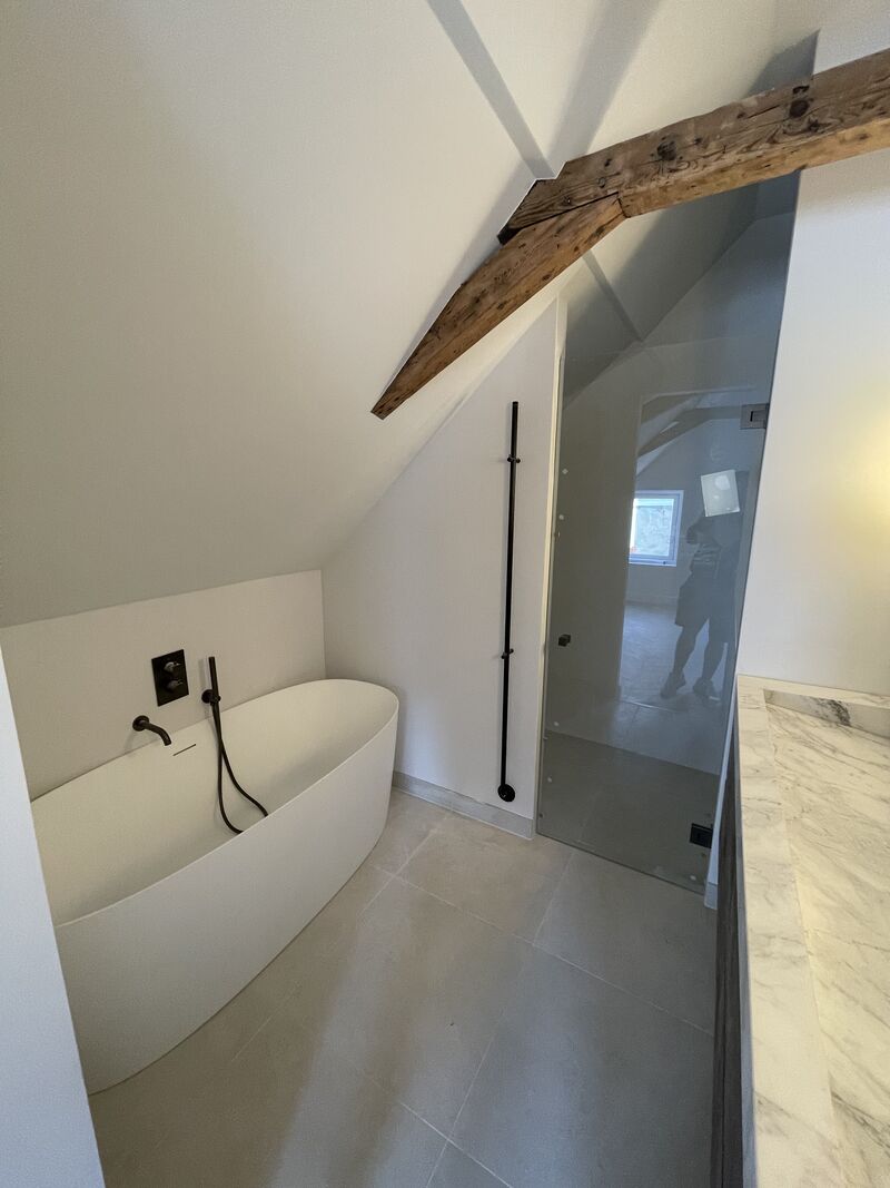 Badkamer met vrijstaand bad onder een houten balk na een renovatie