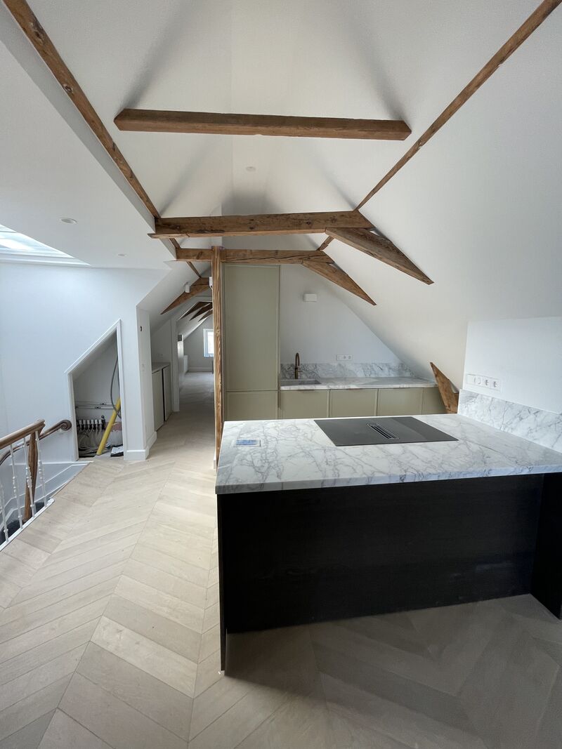 Keuken met marmeren eiland en behouden houten balken, turn-key appartement Amsterdam