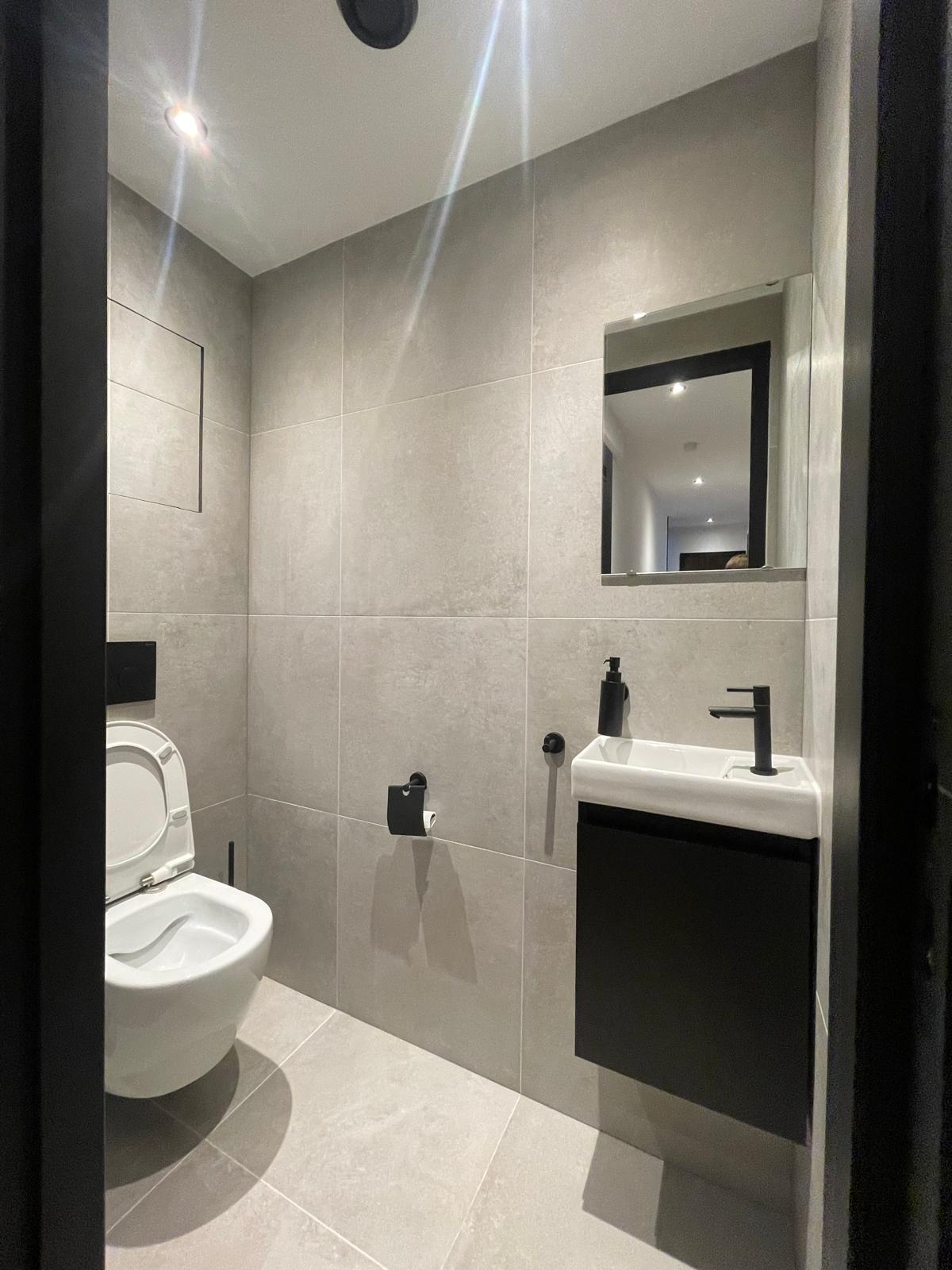 Sleek toilet with grey tiles and black sanitaryware in the Tarwewijk