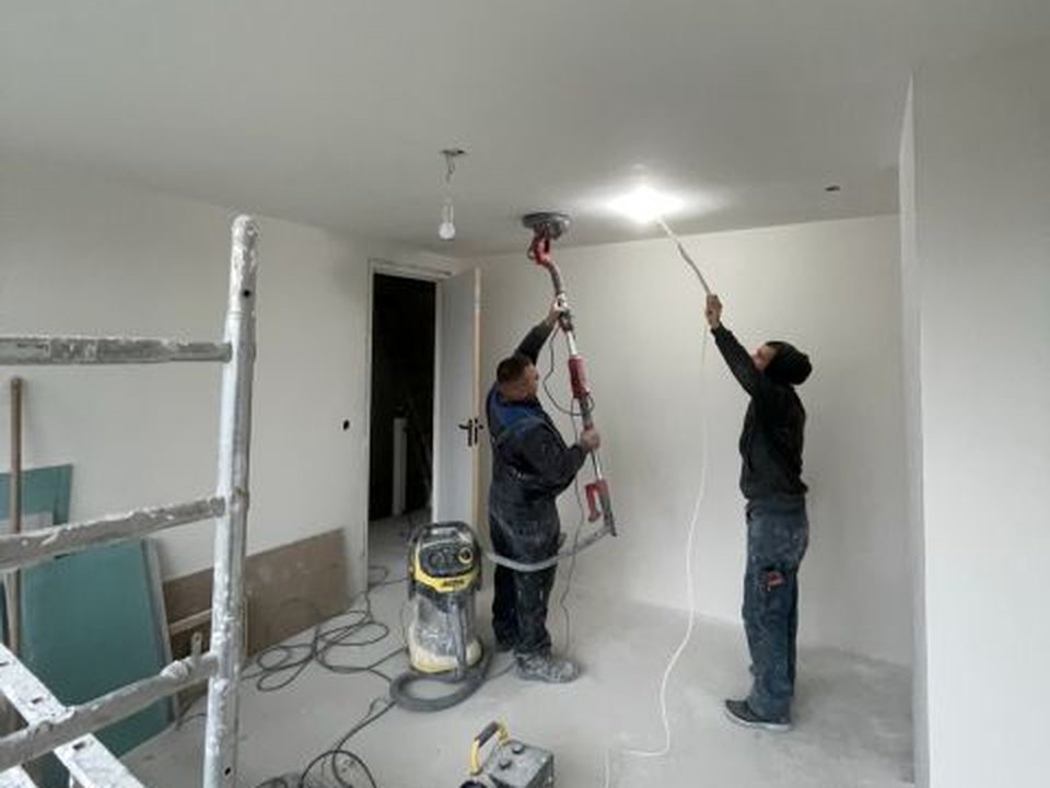 Twee vakmensen van Rotterdamse Bouwbedrijf aan het werk tijdens een woningrenovatie in Rotterdam